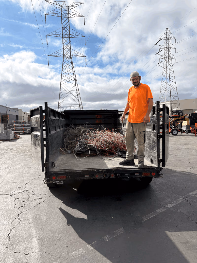 Haynes Industrial worker in an orange shirt standing in a dump trailer loaded with copper wire